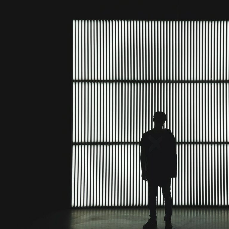 silhouette photo of a person standing near wall in dark room