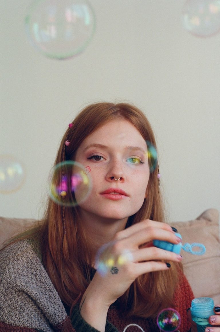 a woman sitting on a couch blowing bubbles