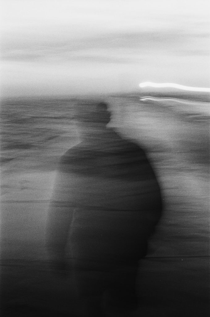 a blurry photo of a man walking on the beach