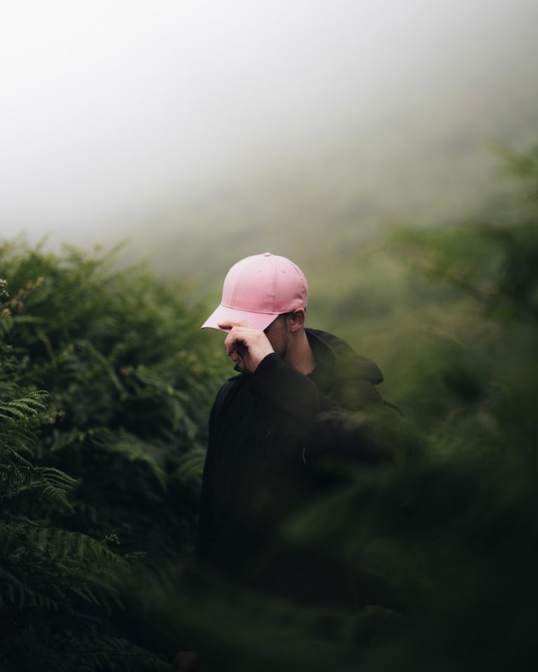 A person wearing a pink hat walking through a forest