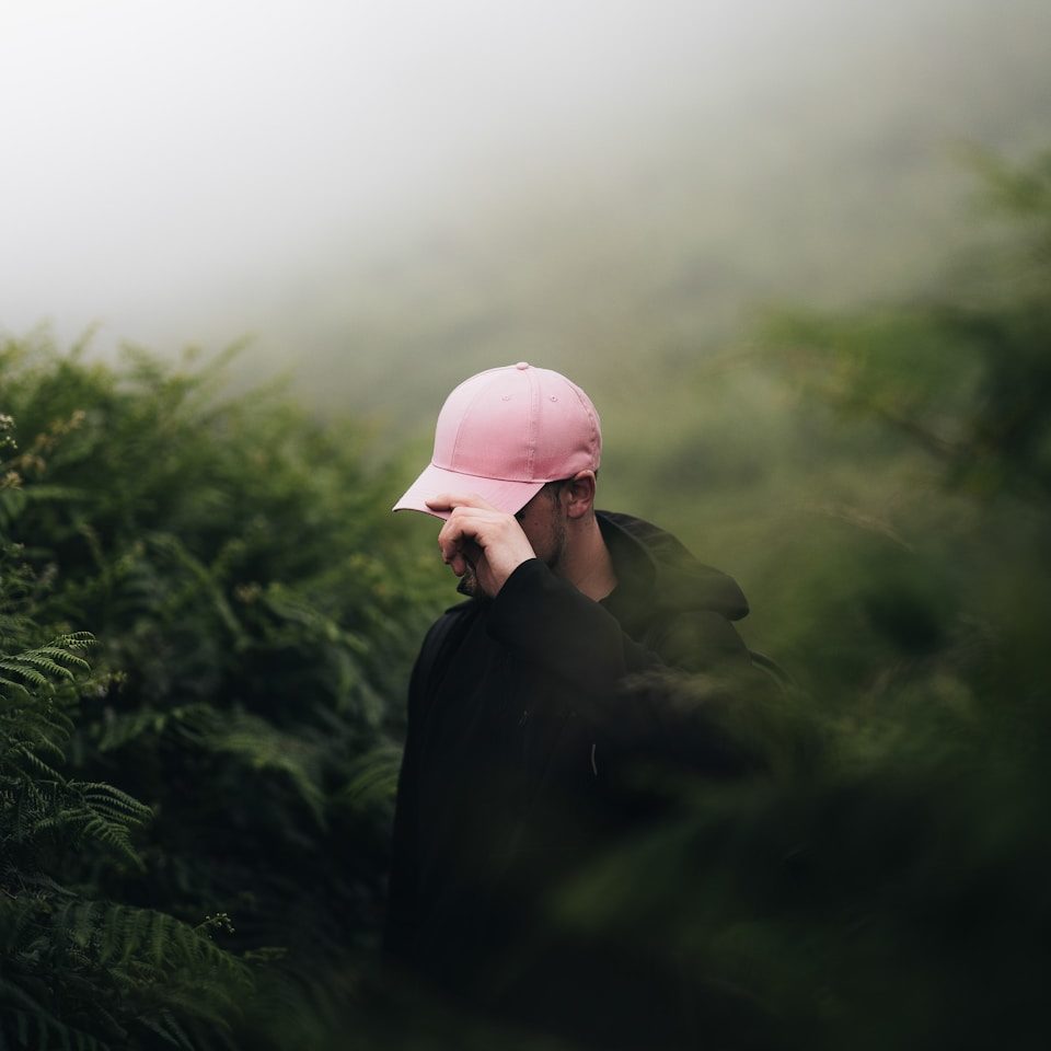 A person wearing a pink hat walking through a forest