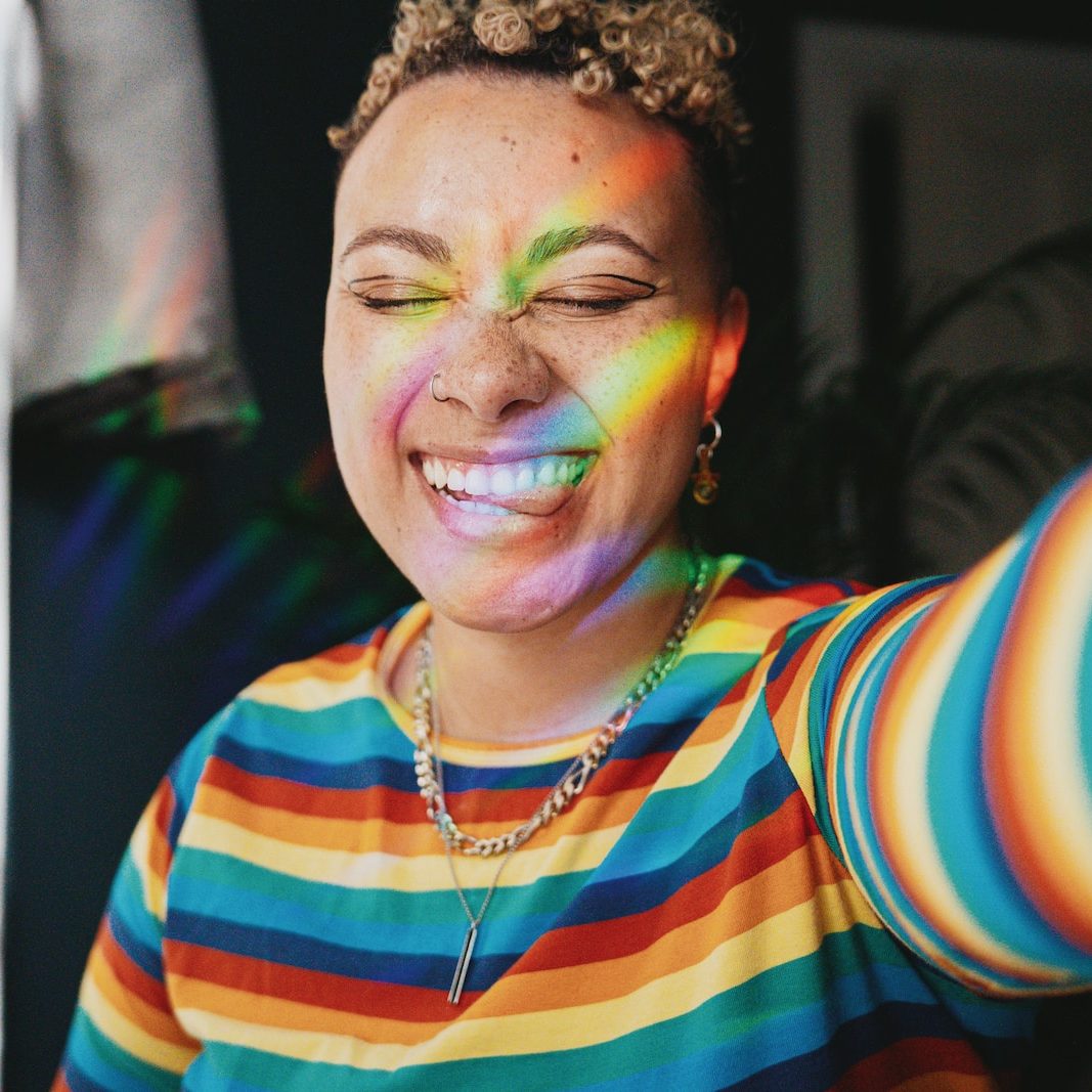 Portrait of nonbinary autistic person wearing a rainbow sweater