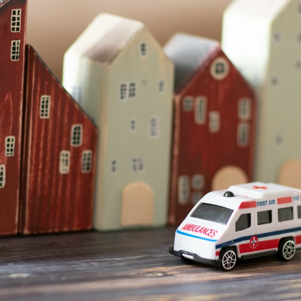 a toy ambulance car next to a row of buildings